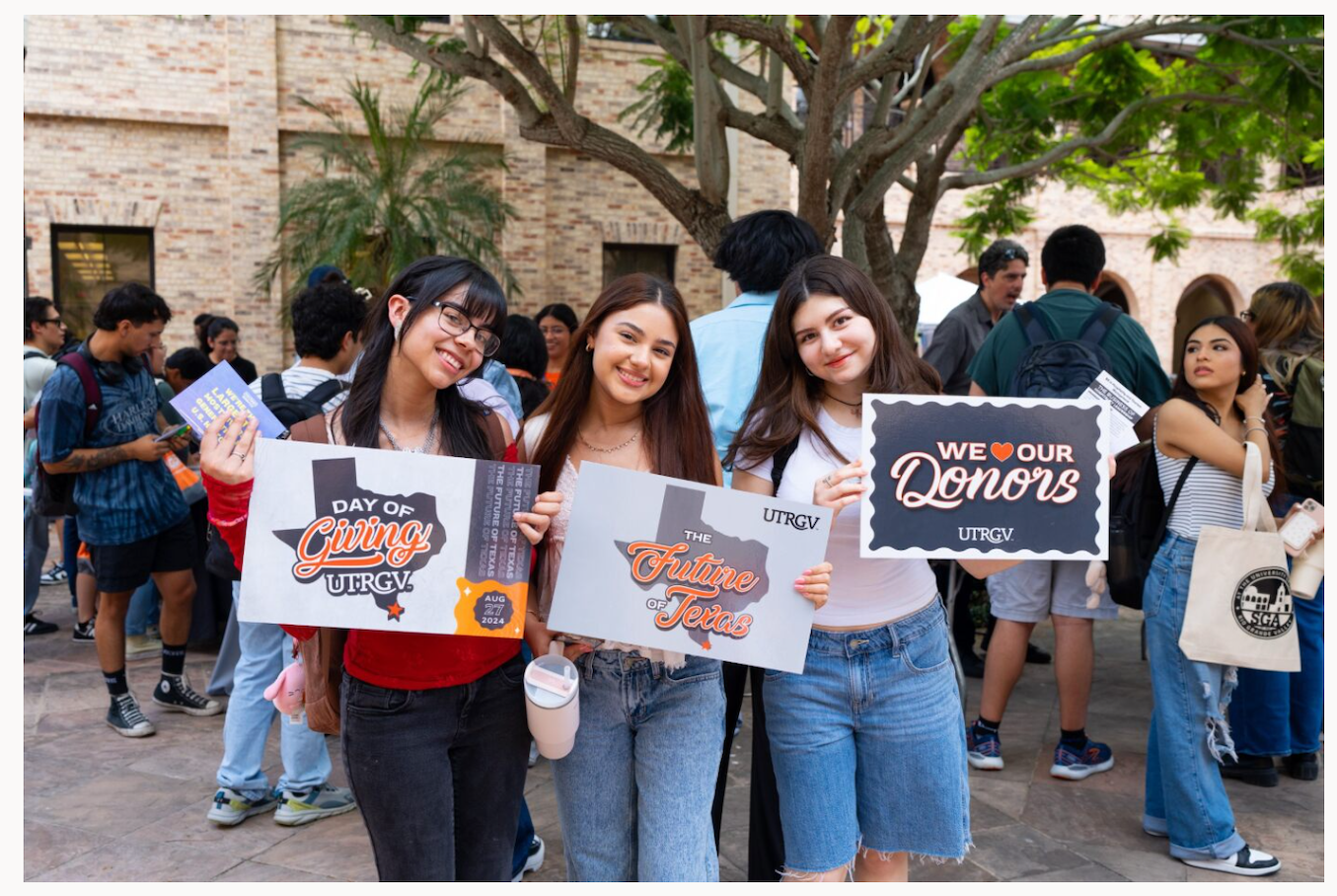 Three UTRGV students hold up signs thanking donors during UTRGV Day of Giving.